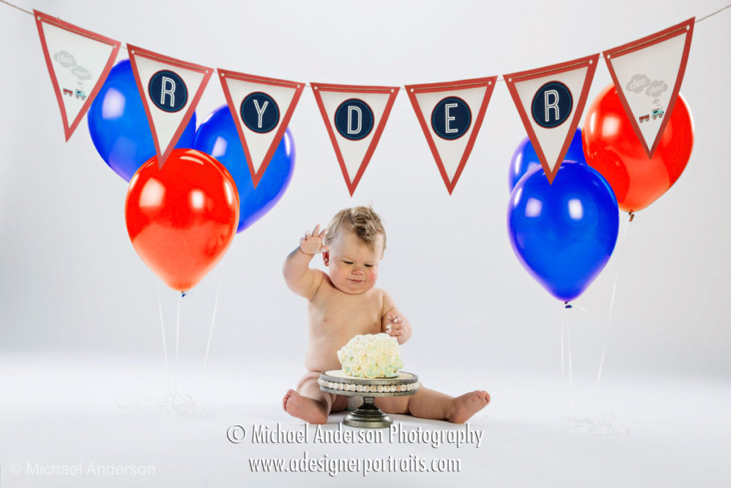 A cute one-year-old baby boy celebrates his first birthday with balloons and cake!