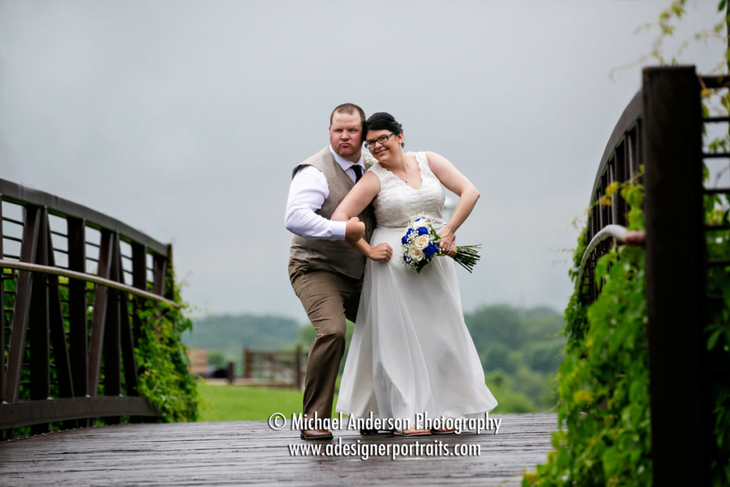 Elm Creek Park Reserve wedding photography of the bride and groom in a wrestling pose on the bridge.
