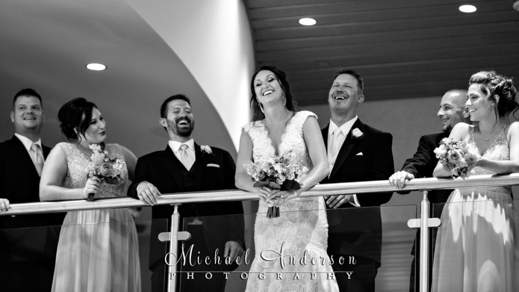 Mystic Lake Casino wedding photos of a fun, candid moment with the wedding party on a balcony. Image taken at the new Mystic Lake Center at Mystic Lake Casino in Prior Lake, MN.