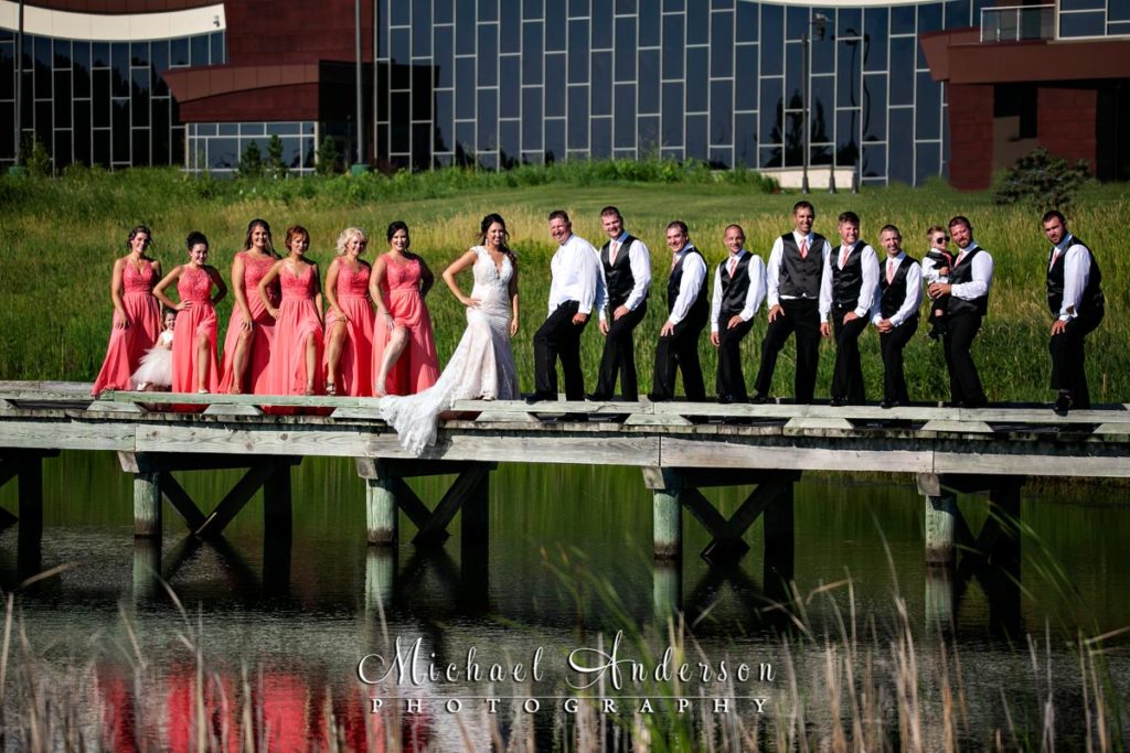 Mystic Lake Casino wedding pictures of the whole wedding party on a wooden bridge. Wedding photo taken at The Meadows at Mystic Lake Golf Course at Mystic Lake Casino in Prior Lake, MN.
