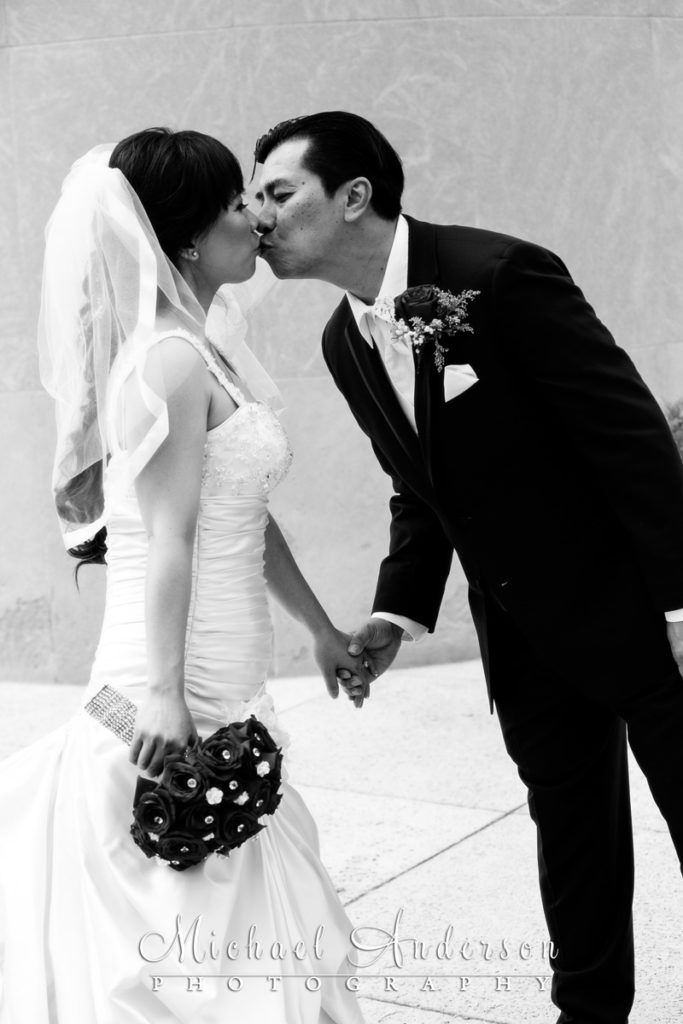 A nice black and white Church of Saint Columba wedding photo of the bride and groom kissing outside in front of the church.