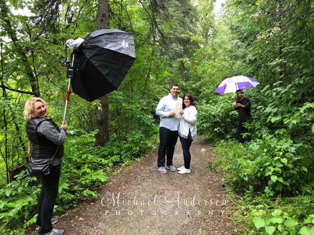 Behind-the-scenes engagement photo of Casey and Cassie in the rain at Lester River Park in Duluth, MN.