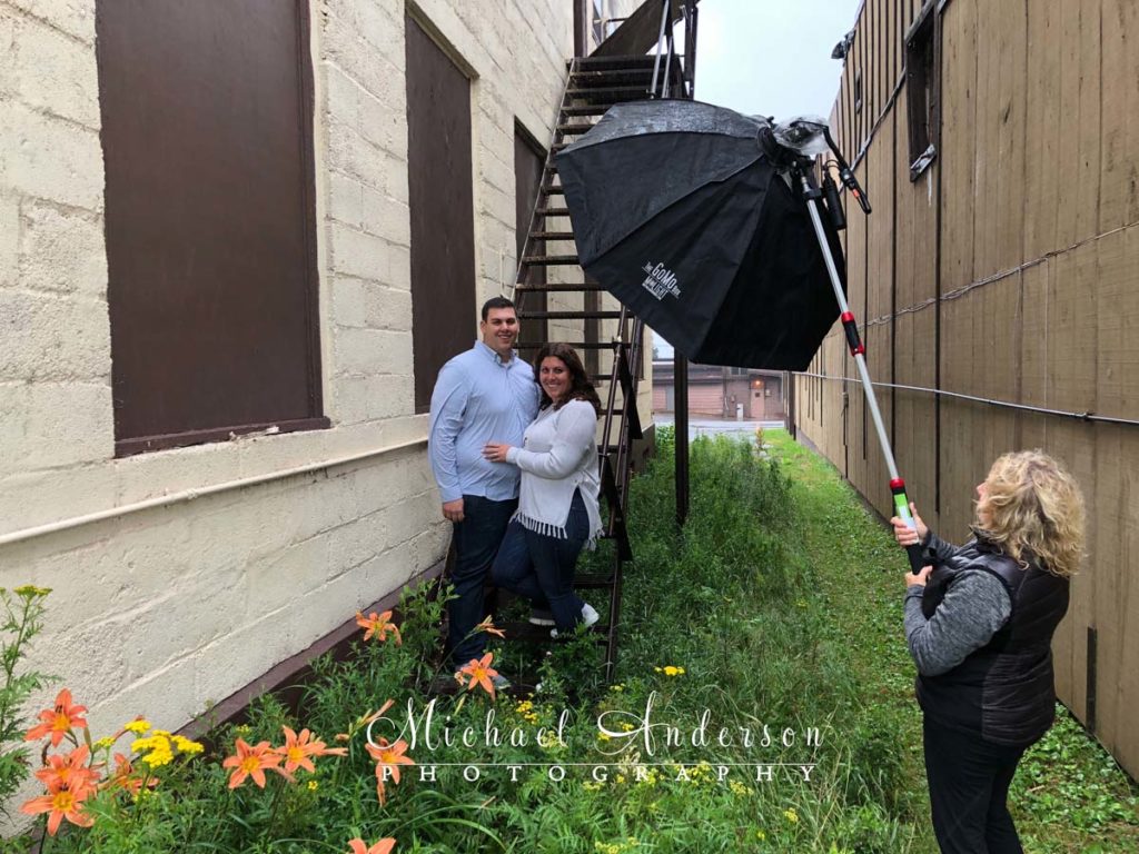 Behind-the-scenes engagement photo of Casey and Cassie in the rain in Two Harbors, MN.