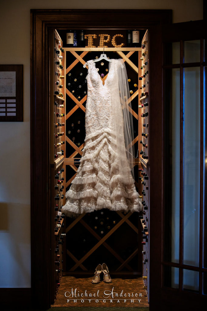 TPC Twin Cities wedding photographs of the pretty brides dress hanging in the wine cellar.