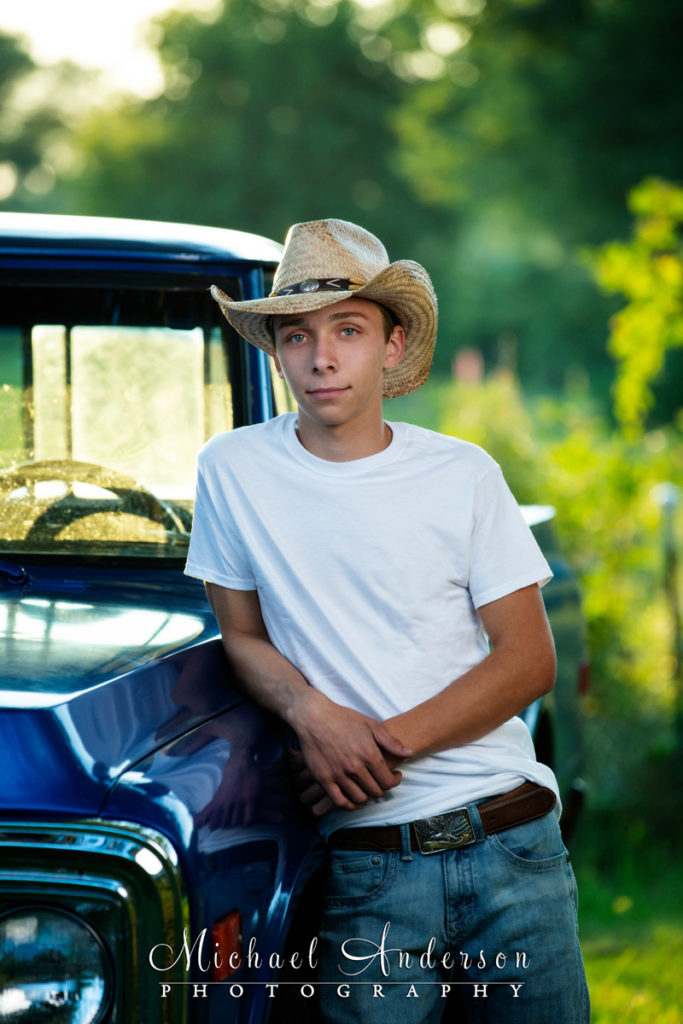 High school senior portrait of a boy and his blue 1969 Chevy truck.