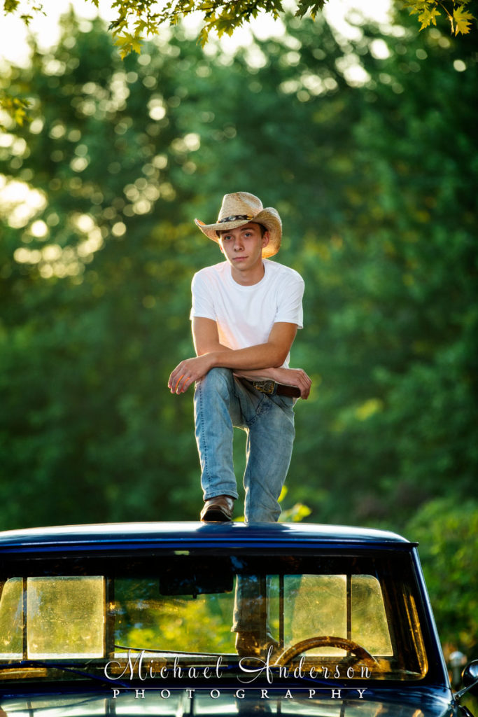 High school senior portrait of a boy standing on his blue 1969 Chevy truck.