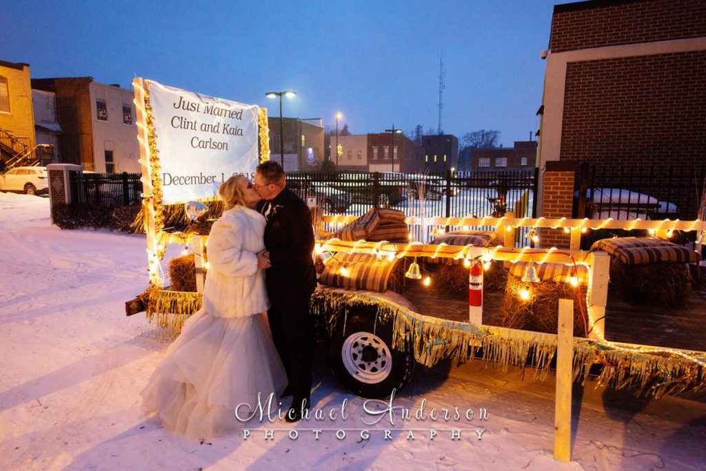 The 3 Ten Event Venue wedding reception photo of the bride and groom kissing by their parade float in a winter storm.