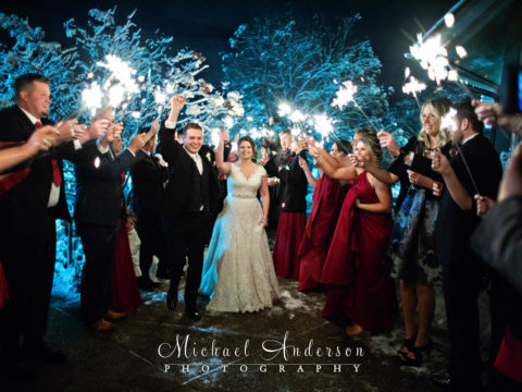 The bride and groom making their way through a sparkler send-off from their wedding party and friends at their Rush Creek wedding reception.