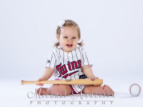 Adorable baby portraits of a one-year-old baby girl wearing a Minnesota Twin jersey.