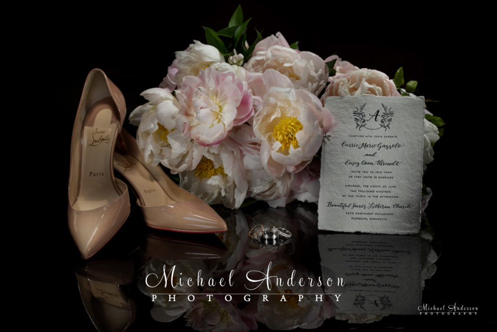 Light painted Beautiful Savior wedding photo of the wedding rings, invitation, bouquet, and the bride's shoes.
