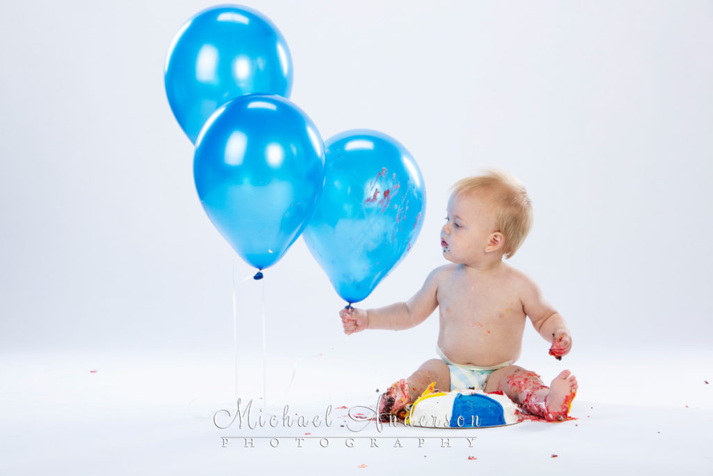 Birthday cake photos of a one-year-old boy holding a blue balloon.