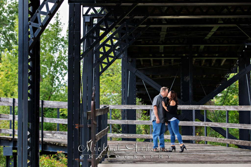 Little Log House Pioneer Village engagement photograph of a couple kissing under the replica of the Hastings Spiral Bridge.