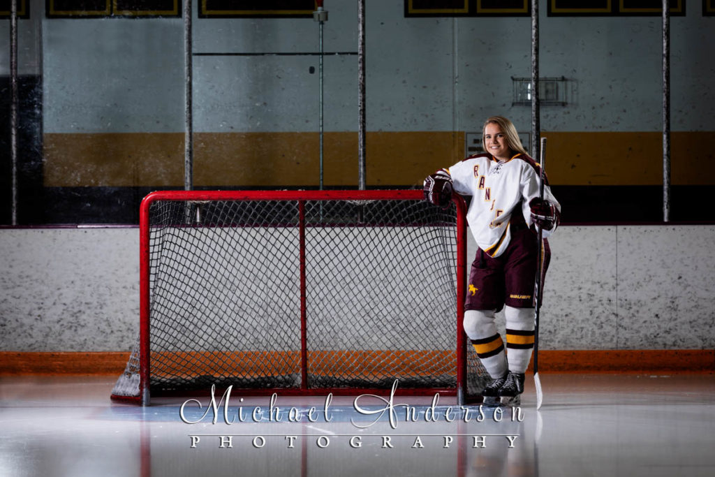 Senior photo of a Forest Lake girls hockey player by the goal at Lichtscheidl Arena.
