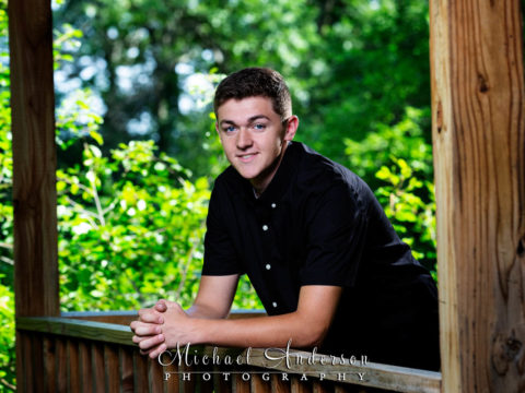 Senior portraits at Silverwood Park of a boy in a wooden structure in the dense woods.