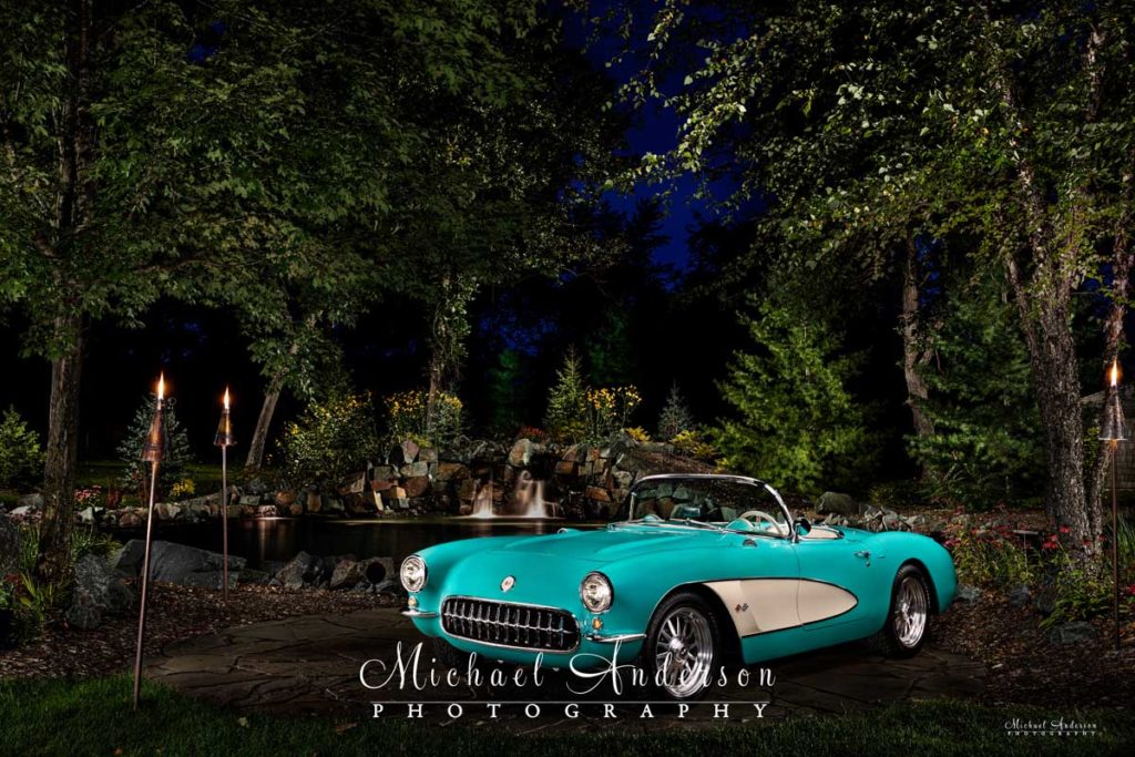 A stunning light painted photograph of a mint condition 1957 C1 Corvette by a waterfall.