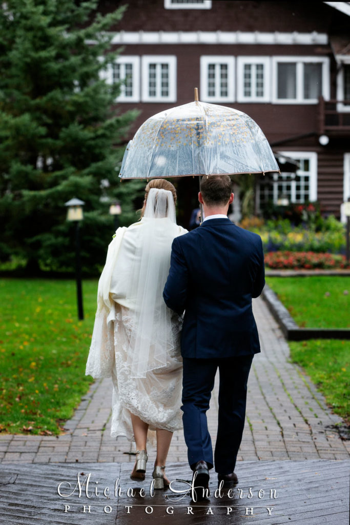 Bride and groom under an umbrella at Grandview Lodge in Nisswa, MN.