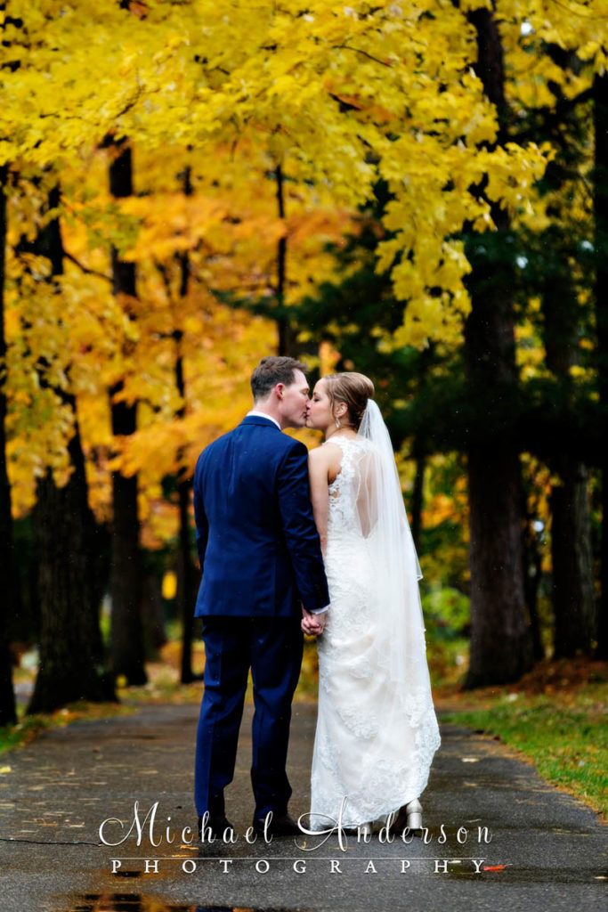 The bride and groom sharing a kiss under a stunning fall color display during their Grandview Lodge wedding day.