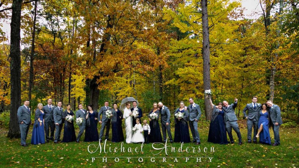 The bride, groom, and their entire wedding party out in the pretty fall colors (and the falling snow) during their Grandview Lodge wedding day.