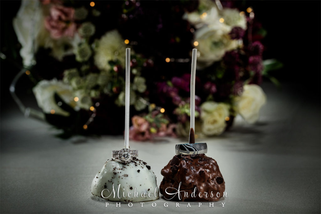 A light painted wedding photograph of the couple's wedding rings on two cake pops.