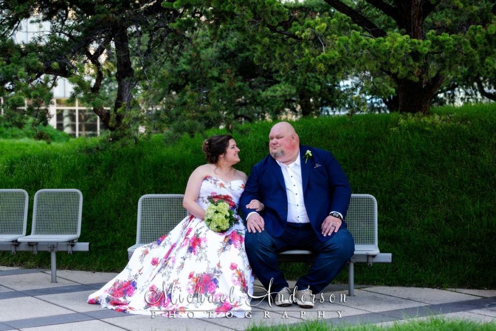 A bride and groom enjoy a quiet moment on a park bench in downtown Minneapolis, MN.