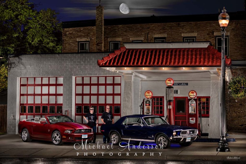 A pair of light painted Ford Mustangs, a 1968 and a 2014, along with their owners. Image created at Gregg's Vintage Restored Gas Station in Carver, MN.