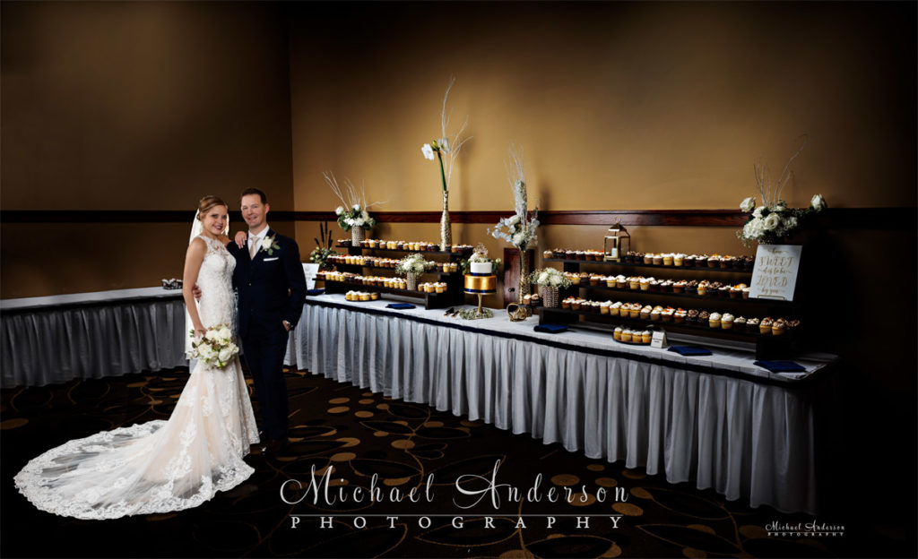 A pretty light painted wedding photo of the bride and groom at their pretty cake table at Grandview Lodge in Nisswa, MN.