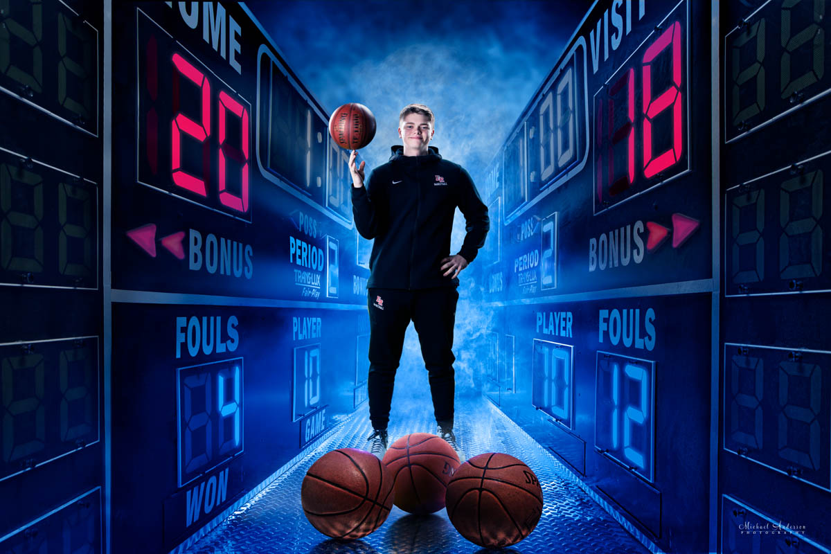 Elk River High School senior portrait green screen composite. A basketball player standing in-between a pair of scoreboards.