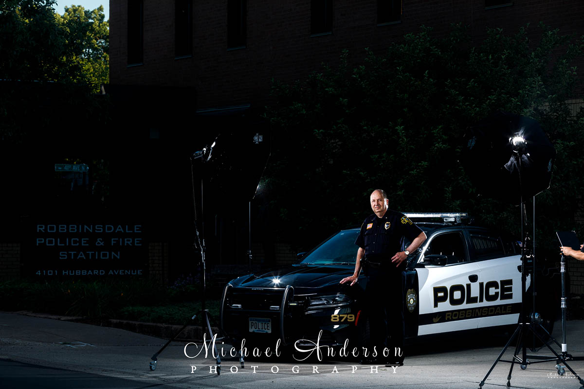 The Robbinsdale, MN Police Chief photographed with a squad car at night.