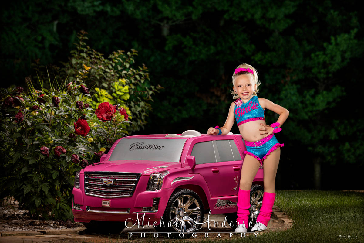 A cool light painting of a pink Cadillac Escalade with a young dancer dressed in a Barbie dance costume.