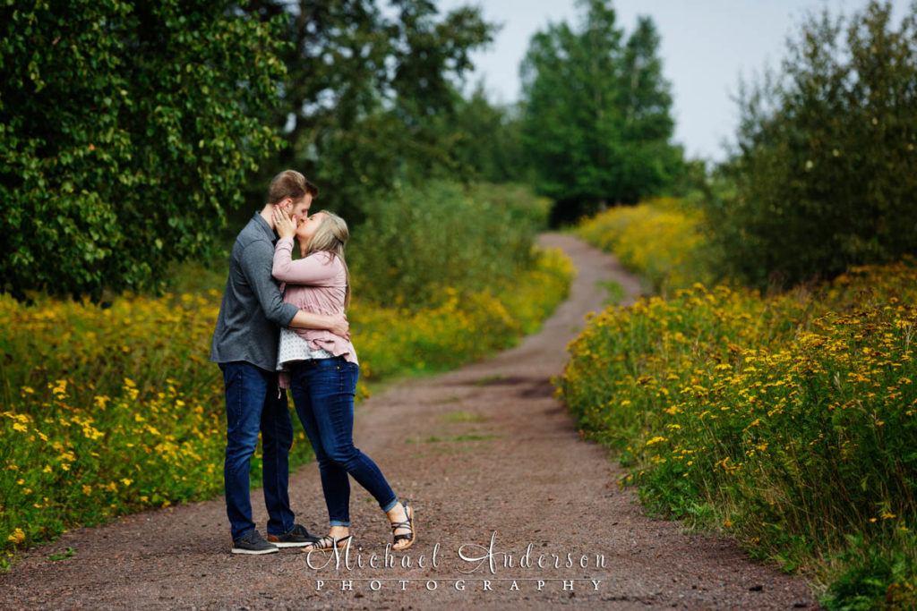 A pretty engagement photograph taken on a flower-lined dirt road.