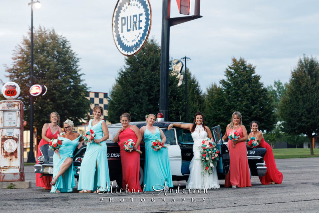 The bride and her bridesmaids posing by the old sheriff's car on display during her Little Log House Pioneer Village wedding reception.