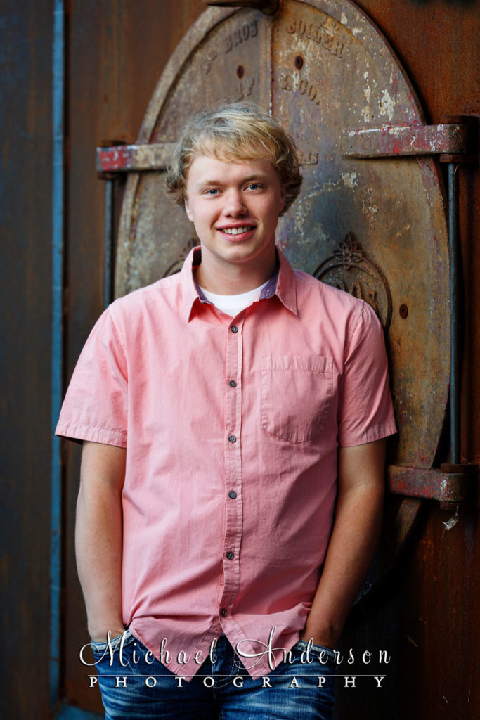 A nice senior photograph of a boy leaning up against a cool wall.