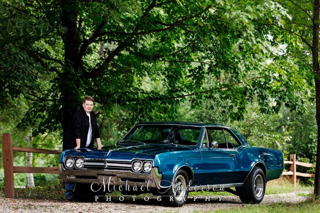 A cool senior photo of a boy and a 1966 Oldsmobile Cutlass F-85.