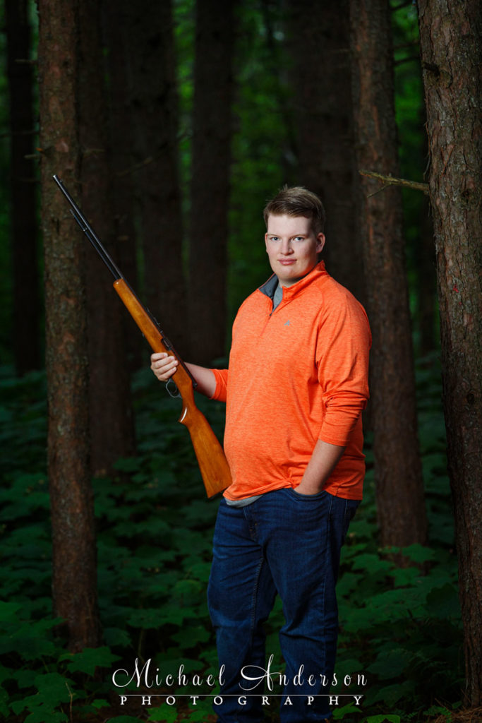 Senior photo of a boy and his great grandpa's .22 long rifle.