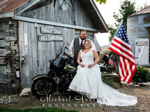 Deglman Farm wedding reception photo of the bride & groom sitting on a Harley Davidson motorcycle.
