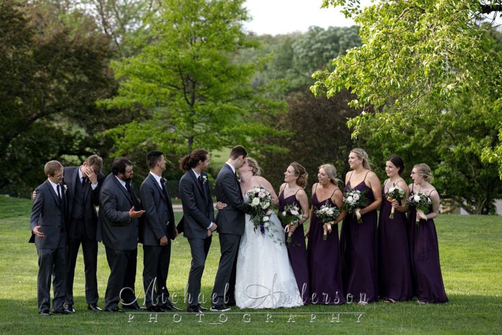A fun wedding party photo of the couple kissing at Golden Valley Country Club in Golden Valley, MN.