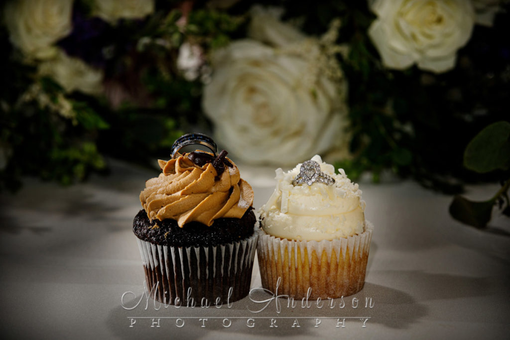 Cute light painted wedding photograph of the wedding rings on top of two cupcakes.