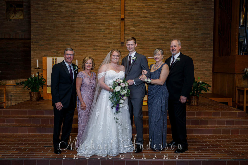 Alex and Alyssa's wedding photo with both sets of parents at the altar at St. Phillip the Deacon Lutheran Church. 