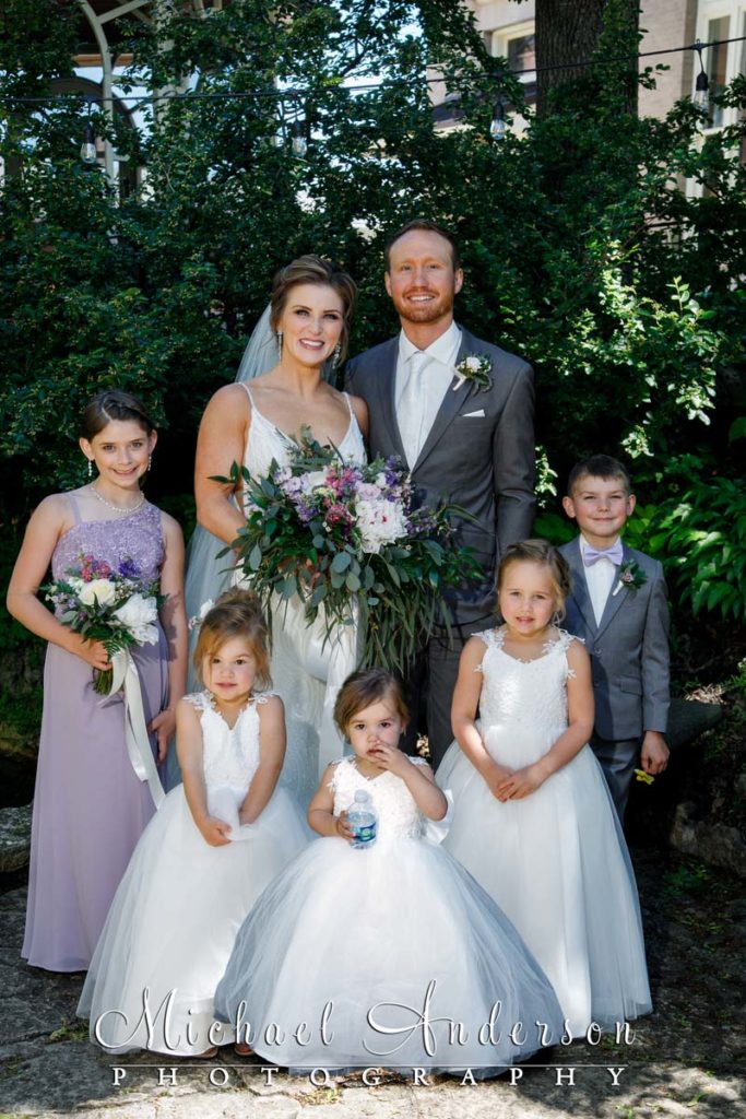 Outdoor wedding photo of the bride and groom with their five junior attendants.