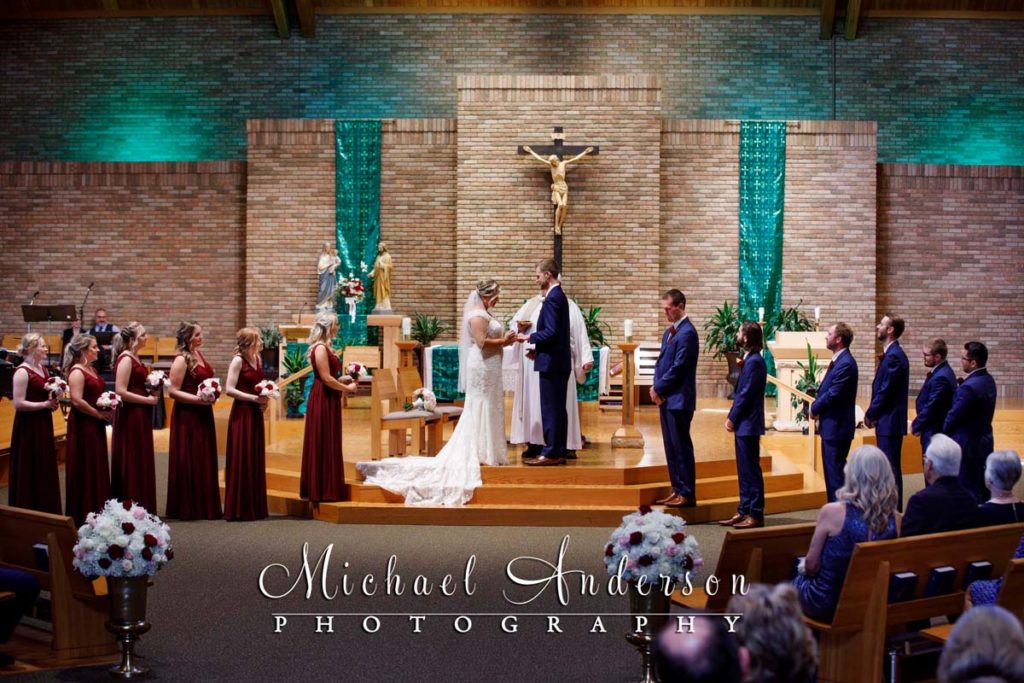 Bride and groom exchanging wedding rings at their St. Joseph of the Lakes wedding ceremony in Lino Lakes, MN.