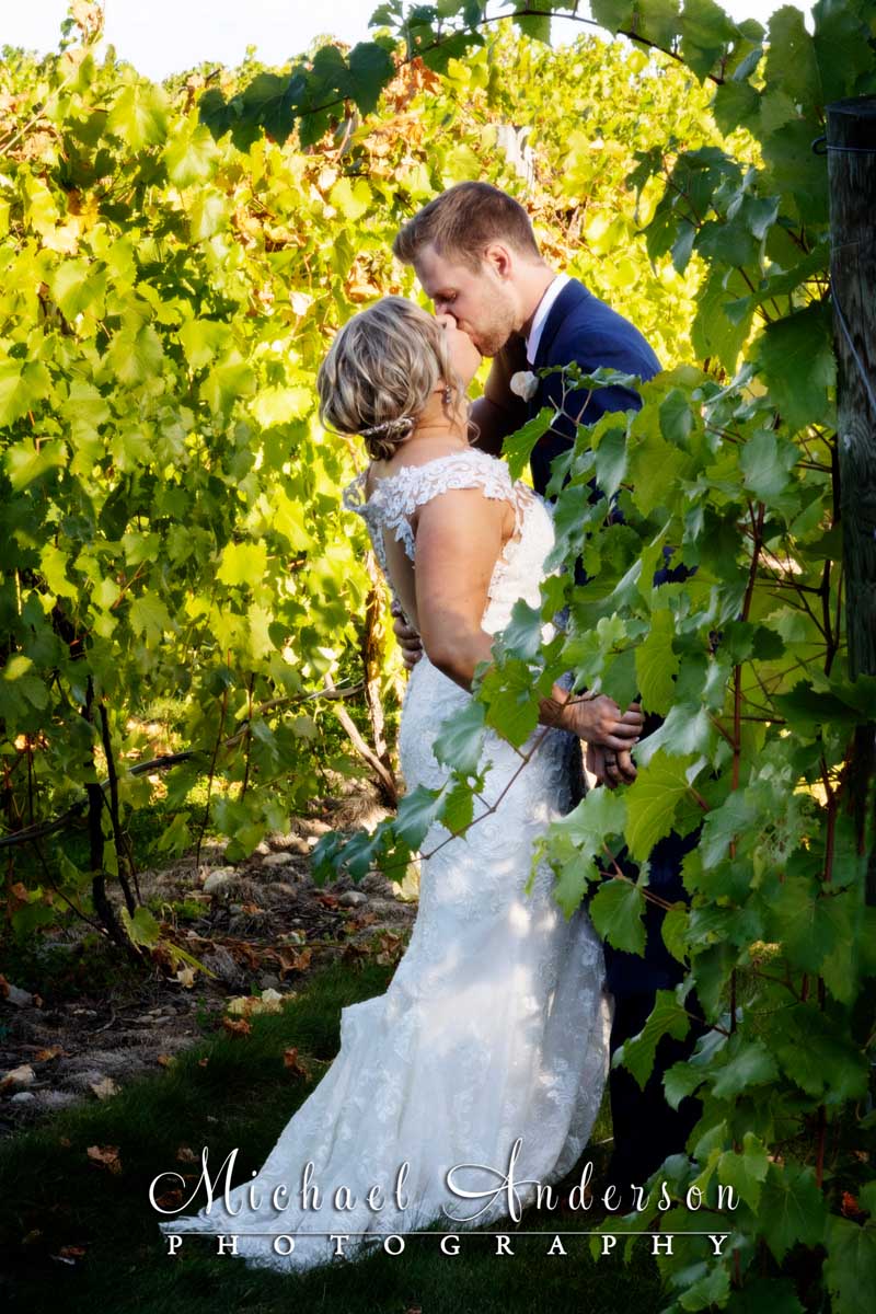 The bride and groom kissing in the vineyard during their 7 Vines Vineyard wedding reception.