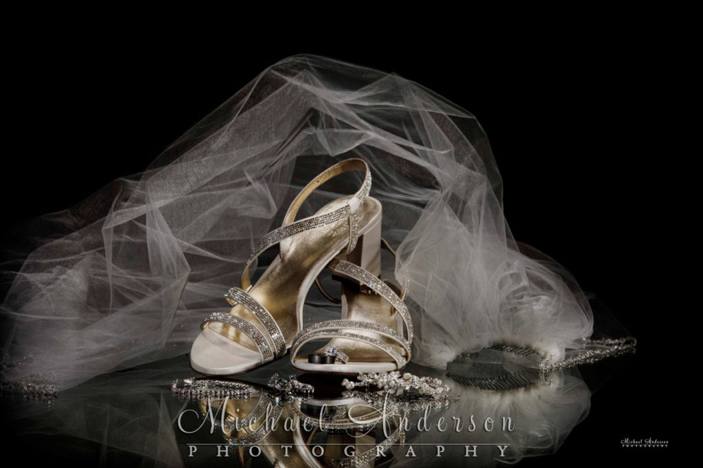 A pretty light painted photograph of the bride's shoes, rings, veil, and jewelry.
