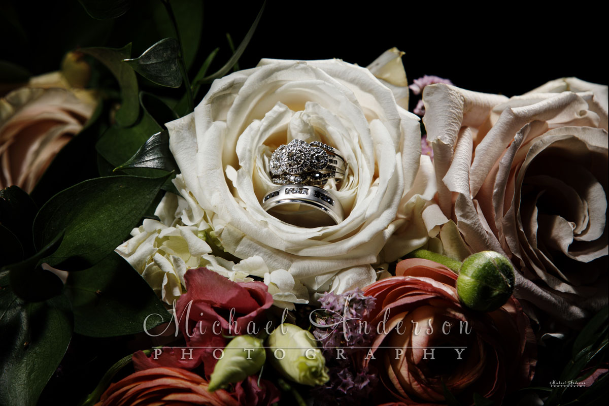 A pretty light painted wedding photo of the wedding rings in a white rose.