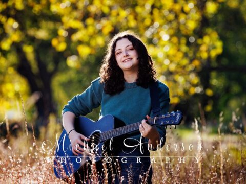 A girl with her guitar in the pretty fall colors during her senior photos at Long Lake Regional Park in New Brighton, MN.