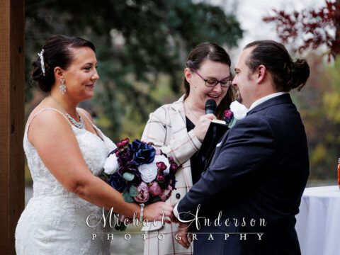 A cute couple exchanges their wedding vows during their pretty fall wedding ceremony at the Chart House in Lakeville, MN.