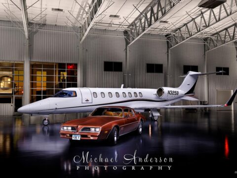 A light painted photograph of a Learjet 45XR and a 1978 Pontiac Firebird.