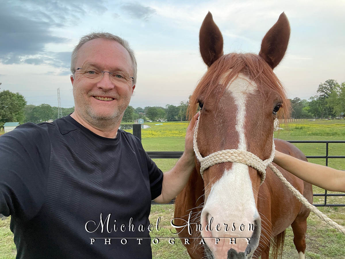 Selfie of Michael Anderson with a racehorse named Boujee.