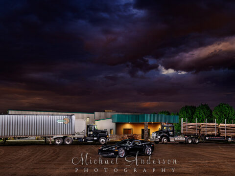 A cool light painted photograph of a Kenworth T880, a Mack P164T, and a 2006 Corvette Z06 at the headquarters of Fornengo Forest Products in Danbury, WI.