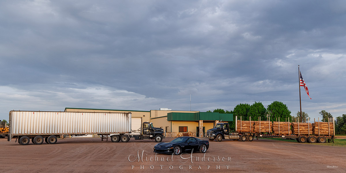 A photograph of a Kenworth, a Mack, and a 2006 Corvette at the headquarters of Fornengo Forest Products in Danbury, WI.