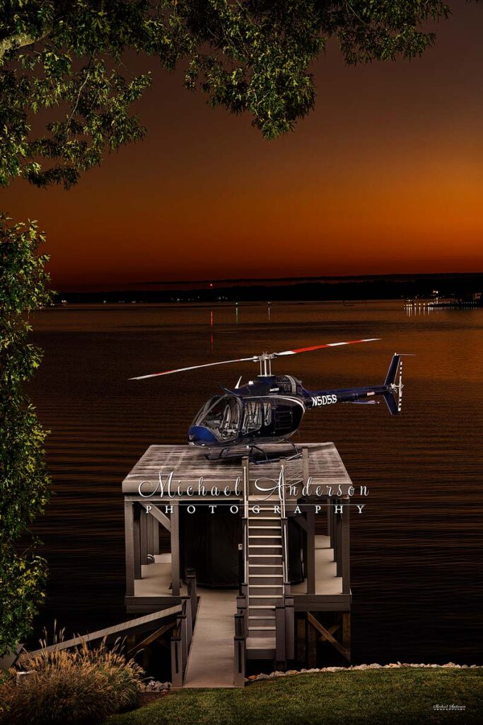 A stunning light painted photograph of a Bell 505 Helicopter on a helipad over Lake Norman in North Carolina.